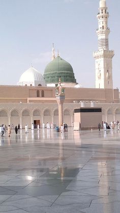 many people are walking around in front of a large building with a green dome on top