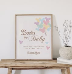 there is a sign that says books for baby on the table next to a potted plant