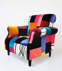 a colorful patchwork chair sitting on top of a white floor next to a wall