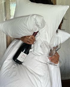 a woman holding two wine glasses under a pillow