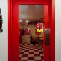 a red door with a coca - cola sign on the side and a checkered floor