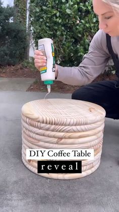 a woman kneeling down with a coffee table made out of wicker and paint rollers