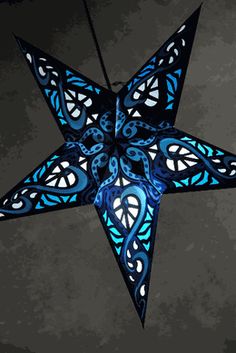 a blue and black star hanging from the ceiling with lights on it's sides