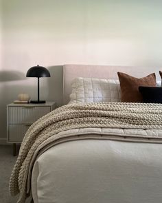 a bedroom with a bed, night stand and lamp on the side table in front of it