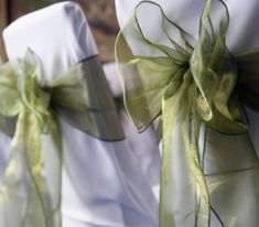 two white chairs with green ribbons tied to the back of them, sitting next to each other