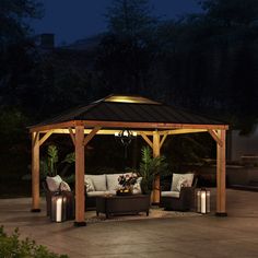 an outdoor gazebo lit up at night with patio furniture and lighting on the ground