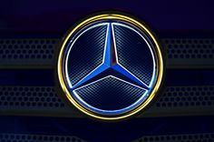 the mercedes logo is illuminated in yellow and blue colors on a car grill or grille