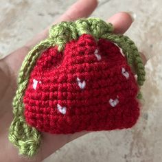 a crocheted strawberry with white hearts on it's shell is held in a persons hand