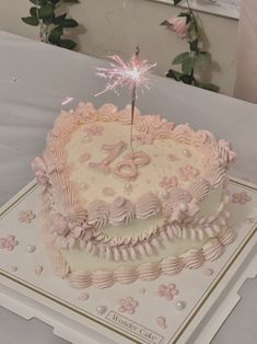 a pink and white birthday cake with a sparkler on top