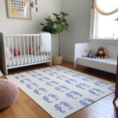 a baby's room with a white crib and blue elephant rug on the floor