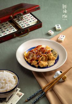 a white plate topped with meat next to rice and chopsticks on top of a table