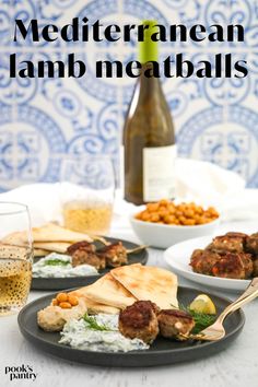 mediterranean lamb meatballs on a black plate with wine and crackers in the background