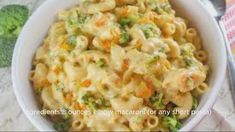 a bowl filled with macaroni and cheese on top of a table next to broccoli