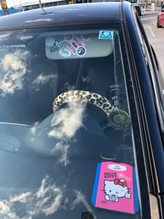 a hello kitty sticker on the windshield of a car with clouds in the background