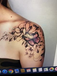 a woman's shoulder with flowers and a butterfly tattoo on her left shoulder, next to a computer screen