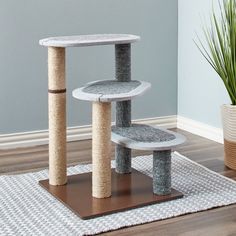 a cat tree in the corner of a room with a potted plant on the floor