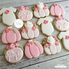 baby shower cookies decorated with pink and white icing are arranged on a wooden table