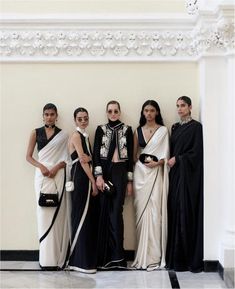 four women standing next to each other in black and white outfits