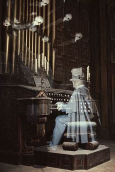 a statue is sitting in front of a pipe organ