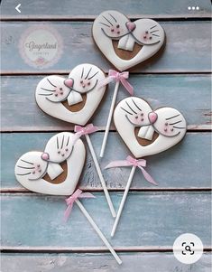 four decorated heart shaped lollipops sitting on top of a wooden table next to each other