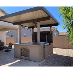 an outdoor bbq with seating and grill in the middle of a patio area next to a house