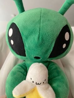 a green alien stuffed animal holding a banana