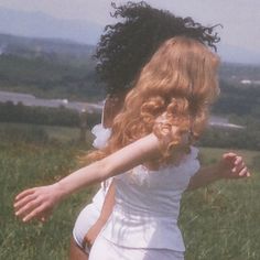 a woman in a white dress is playing with a frisbee on the grass