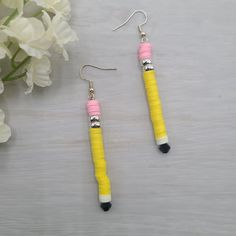 A cute and fun gift for all the teachers or writers in your life! Treat your favorite educator with these super cute pencil earrings. Featuring clay heishi beads to look like the classic yellow #2 pencil, hung from your choice of plated Sterling silver or plated 18k gold French ear wires. Shipped fast and free in a gift box with ribbon and gift tag, ready for gifting.      * Lightweight, fun earrings look like pencils      * Measure approximately 2⅞" long      * Delivered ready for gifting, with box, ribbon, and gift tag      * Nickel-free French ear wires in either plated Sterling silver or plated 18k gold NOTE: Due to the nature of materials and handmade items, each pair of earrings may measure slightly differently. We do our best to match lengths of earrings to create an even set. We hi Pencil Earrings Diy, Pencil Earrings, School Earrings, Jewelry Making Earrings, Heishi Beads, Back To School Gifts, Fun Earrings, School Gifts, Earring Backs