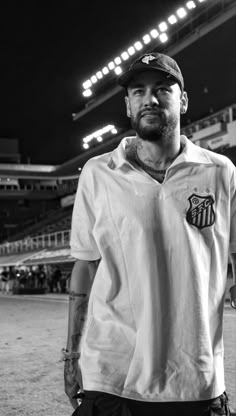 a man standing in front of a baseball field at night with his hand on his hip