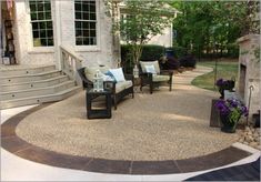 an outdoor patio with chairs, table and fire pit in the middle of it is surrounded by landscaping