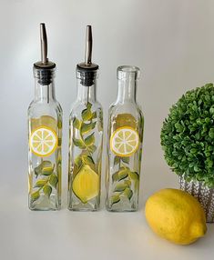 three glass bottles with lemons and leaves in them