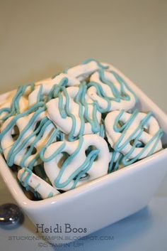 a bowl filled with white and blue frosted pretzels