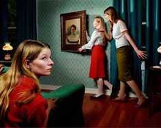 two women and a girl are standing in front of a painting, one is looking at the other