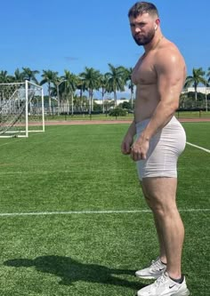 a man standing on top of a lush green field next to a white soccer ball