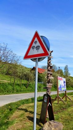 a street sign on the side of a road near a rock and grass covered hill