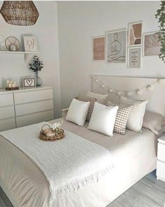 a bedroom with white furniture and pictures on the wall above the bed, along with a wicker basket