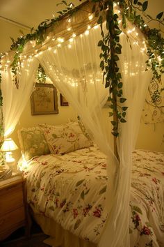 a canopy bed with white curtains and lights on the headboard is decorated with greenery