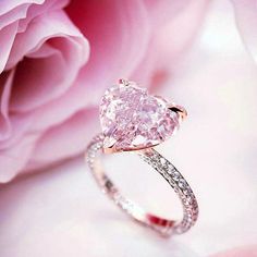 a pink diamond ring sitting on top of a flower