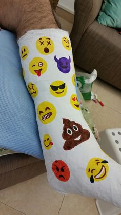 a man is holding his arm with emoticions on it and wearing a cast