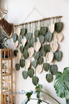 a wall hanging made out of leaves and other plants in a room with white walls