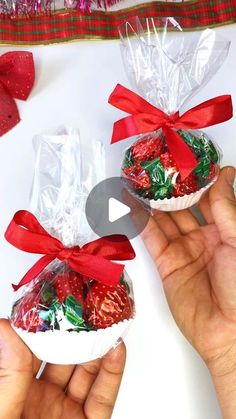 two hands holding candy wrapped in cellophane and tied with red ribbon around them