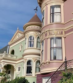 an ornate victorian style house with pink and green paint on the walls, windows and balconies