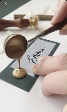 a person holding a pair of scissors and writing on a piece of paper next to a stamp