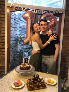 a man and woman standing in front of a cake with the number one on it