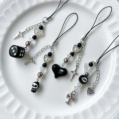 four different necklaces on a white plate with black beads and charms hanging from them