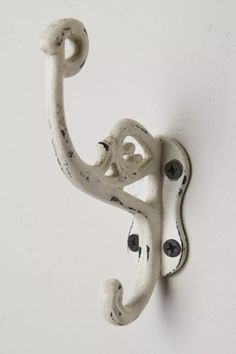 an ornate white hook on the wall with black dots in it's center and bottom part