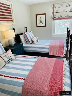 two beds in a bedroom with red, white and blue bedding