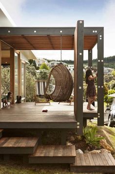 a child swinging on a swing set in front of a wooden deck with steps leading up to it