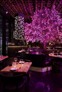 a dining room with tables and purple lighting on the ceiling is lit up by lights