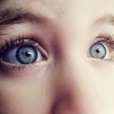 a close up of a child's face with blue eyes and long eyelashes, looking at the camera